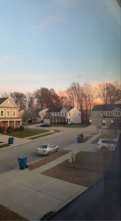 an empty street with cars parked on the side and houses in the backround