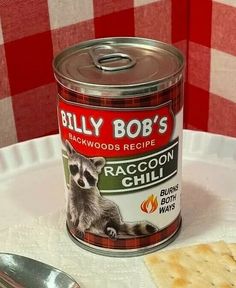 a can of raccoon chilli next to crackers and a spoon on a table