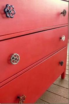 a red dresser with knobs and handles on it