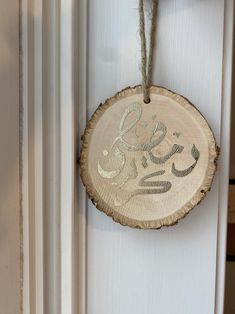 a wood slice hanging on a door with the word love spelled in arabic and an ornament