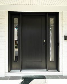 a black front door on a white brick building with two sidelights and glass panels