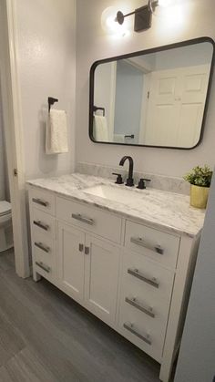 a bathroom with white cabinets and marble counter tops