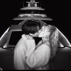 two women kissing each other on the back of a boat in front of a yacht