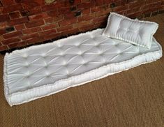 a white mattress sitting in front of a brick wall