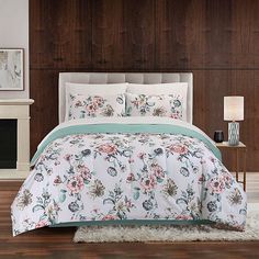 a bed with floral comforter and pillows in a room next to a fire place