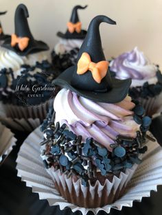 cupcakes decorated in black and white frosting with witches hats on top, all topped with sprinkles