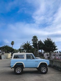 a blue and white jeep parked on the side of a road next to palm trees