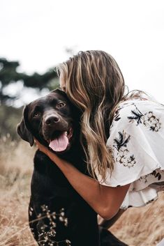 a woman hugging her dog in a field