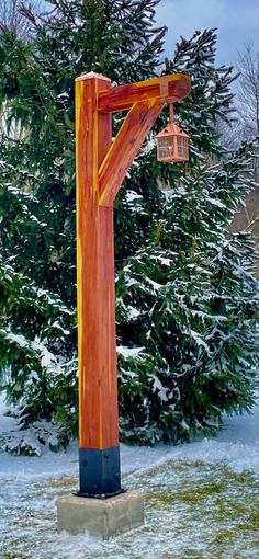 a wooden cross with two lanterns hanging from it's sides in front of snow covered trees