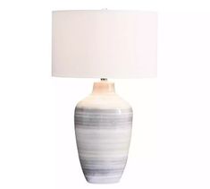 a lamp with a white shade on it and a blue striped vase next to it