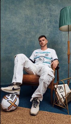 a man sitting in a chair next to a lamp and soccer ball on the floor