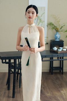 Exude grace and sophistication with this elegant ivory white halter neck qipao, features a minimalist and modern halter neck design with a high collar and keyhole neckline, providing a sleek and contemporary take on traditional Chinese fashion. Made from high-quality, lightweight fabric, this dress offers a comfortable and breathable fit, perfect for any occasion. This qipao falls to a midi length, offering a modest yet stylish look suitable for various occasions, from formal events to casual ga Chinese Collar Wedding Gown, White Qipao Wedding Dress, Turtle Neck Wedding Dress, White Qipao, Traditional Chinese Fashion, Chinese Collar Dress, Qipao Wedding Dress, Bday Dress, Qipao Wedding