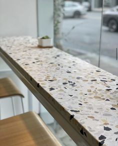 a table with two chairs next to it in front of a glass wall and parked cars