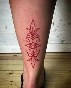 a woman's foot with a red tattoo design on the bottom of her leg