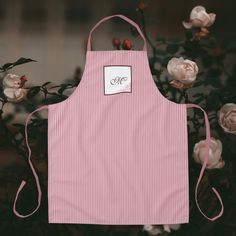 a pink striped apron with a white monogrammed tag on it and flowers in the background