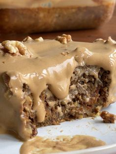 a piece of cake on a plate covered in frosting and walnuts with a bite taken out