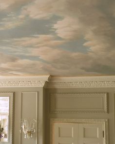 an empty room with white walls and painted clouds on the ceiling above it is a chandelier