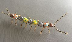 an insect made out of glass beads on a gray surface with one leg bent forward