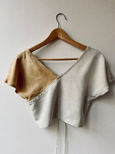 a crop top hanging on a hanger against a white wall with a wooden hanger