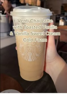 a person holding up a starbucks cup with the words ventti chai latte with toasted vanilla and vanilla sweet cream cold foam