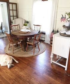 a dog laying on the floor in front of a dining room table