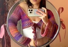 a woman taking a selfie in front of a mirror with her cell phone and sweater on