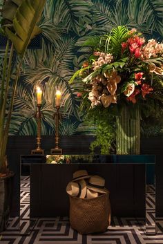 a vase filled with lots of flowers sitting on top of a table next to a plant