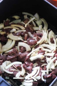 the food is being cooked in the pan on the stove top with onions and meat