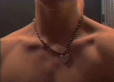 a shirtless man wearing a necklace with a heart on it