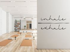 yoga mats are lined up in front of a wall with the words indhale exhale written on it