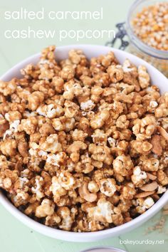 a white bowl filled with caramel cashew popcorn next to another bowl full of nuts