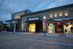 people are walking in front of a store at dusk