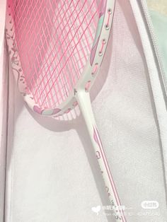 a pink tennis racquet laying on top of a white bag