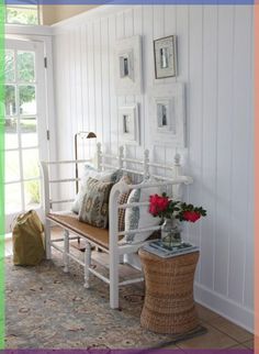 a white bench sitting in the corner of a room with pictures on the wall behind it