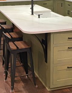 a kitchen island with stools in front of it and an umbrella over the sink