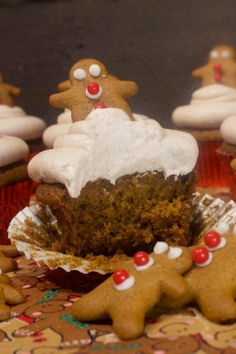 A gingerbread cupcake with a bite out and topped with cream cheese cinnamon buttercream and a tiny gingerbread cookie.