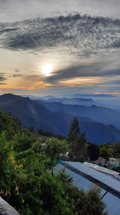 the sun is setting over some mountains and trees