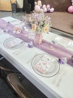 the table is set with plates, silverware and flowers