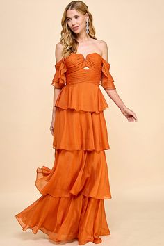 a woman in an orange dress posing for the camera with her hands on her hips