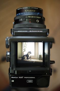 a camera with a dog sitting on the ground in front of it's lens