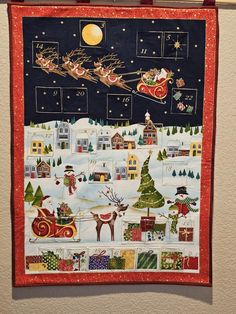 a christmas quilt hanging on the wall with santa's sleigh and reindeers