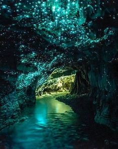 the inside of a cave filled with water and green lights on the ceiling is lit up