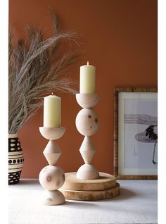 three candles are sitting on a table next to a potted plant