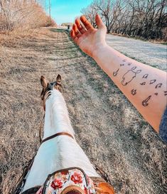 a person holding the hand of a horse with writing on it's arm in an open field