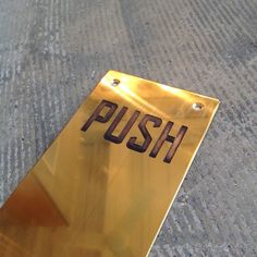 a metal sign that says push on the side of a sidewalk with no people around it