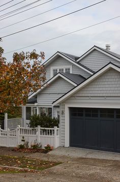 a house with two garages and a white picket fence