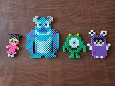 three perlery bead monsters sitting next to each other on a brown surface