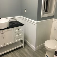 a white toilet sitting in a bathroom next to a sink and vanity with black counter top