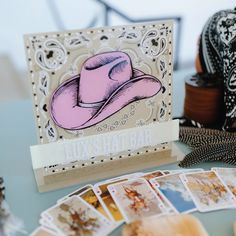 a card with a pink hat on it next to some cards and other items that are sitting on a table