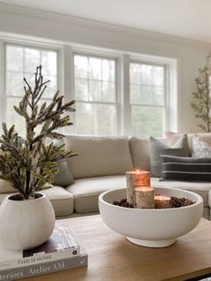 a living room filled with furniture and a lit candle in a bowl on top of a coffee table